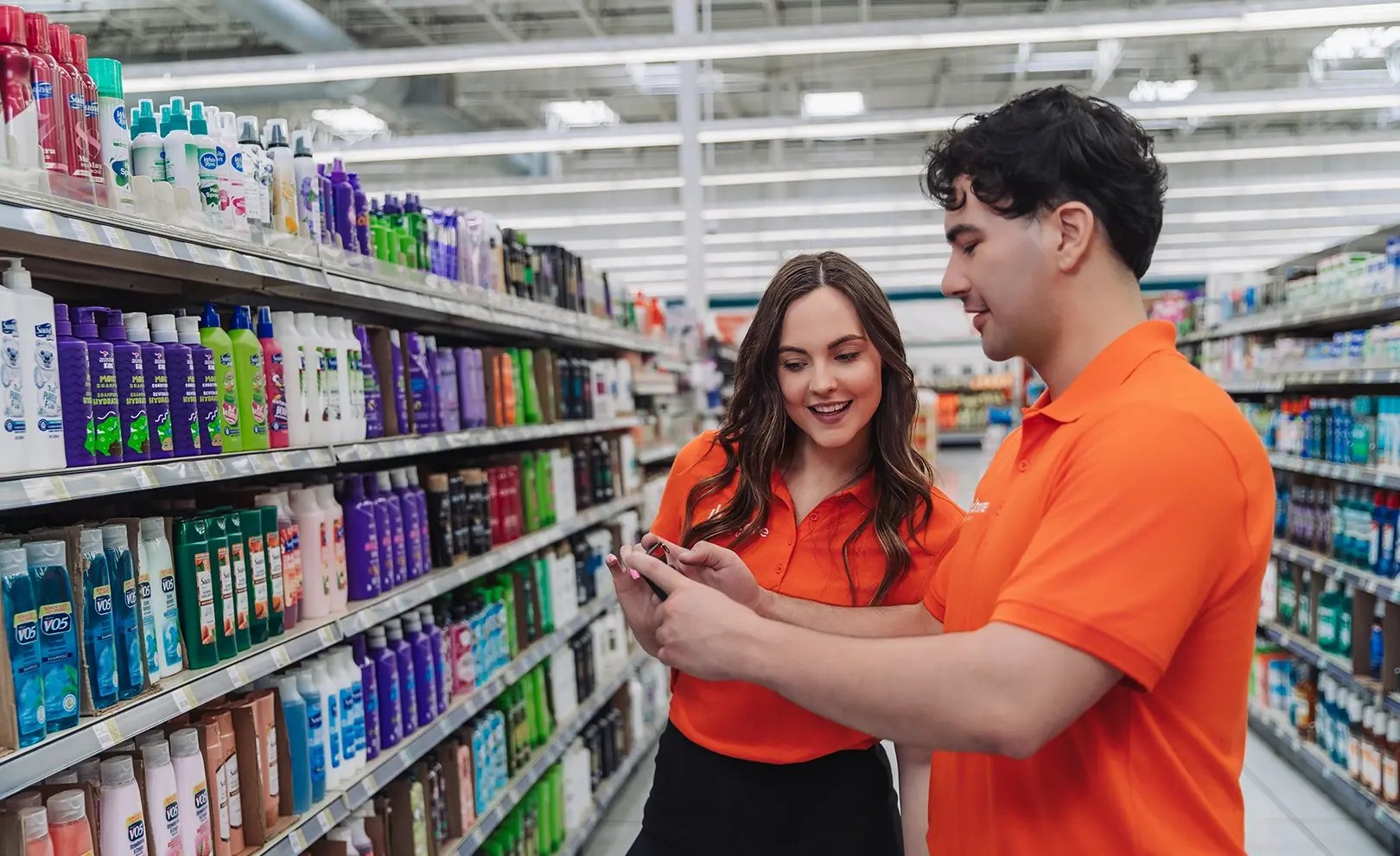 two in store merchandisers work together referencing a planogram